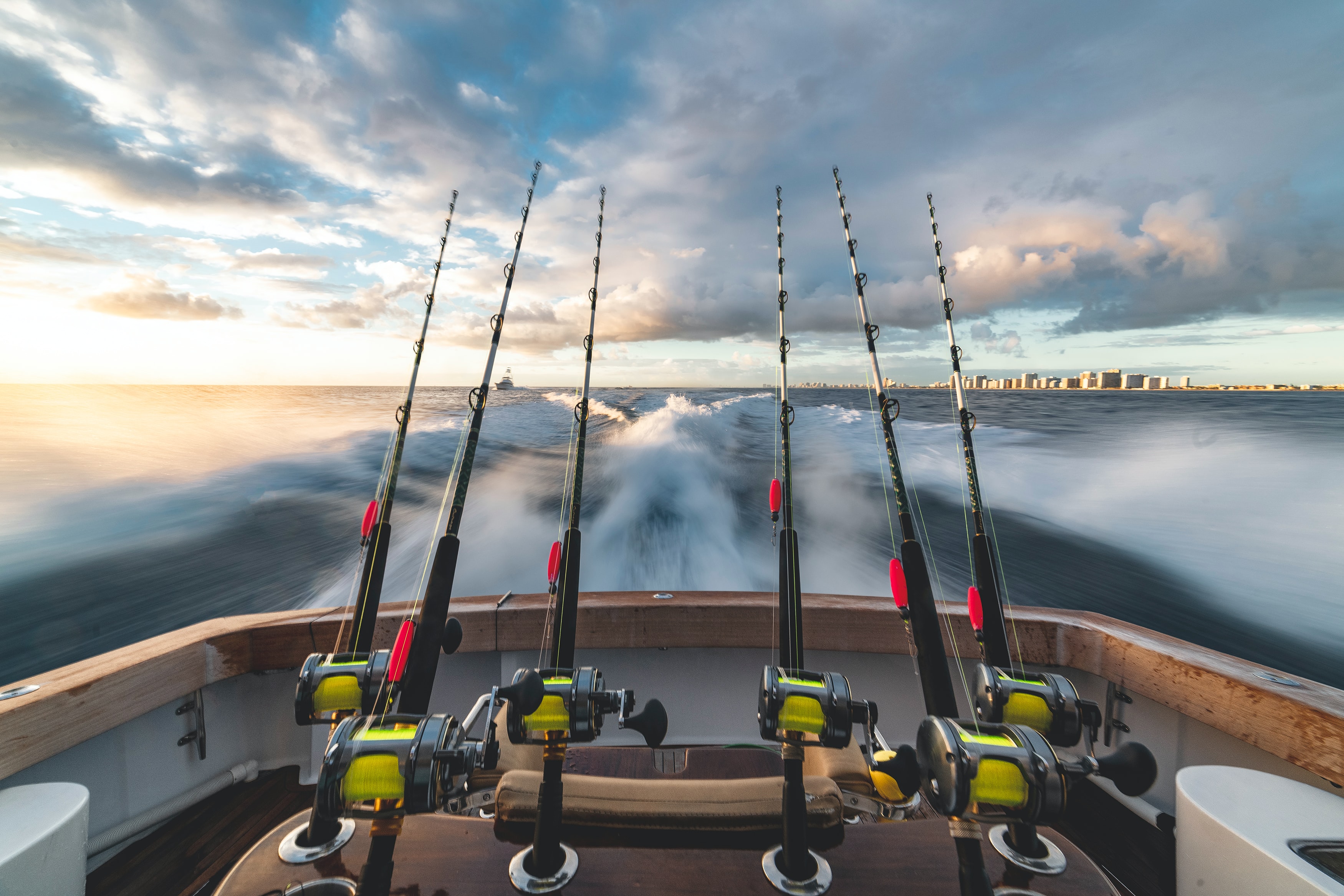 Fishing rods lined up on a charter boat heading out at sunrise