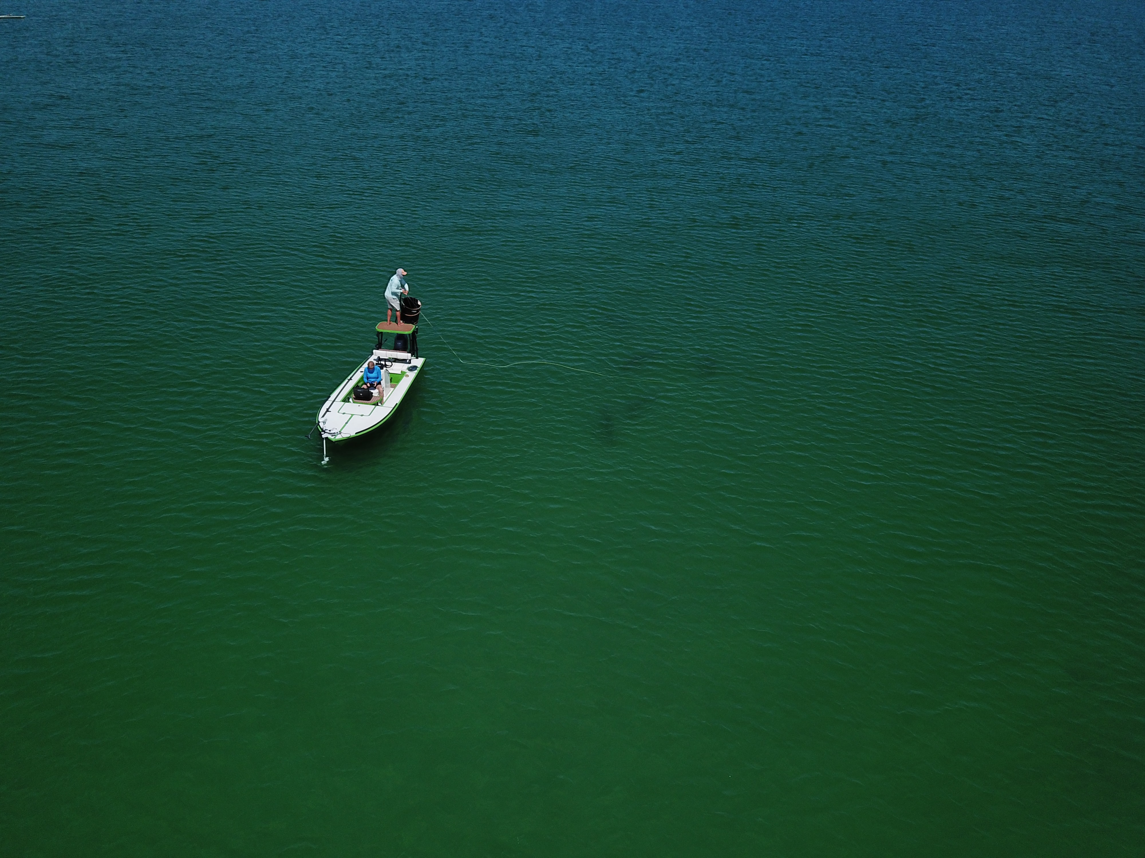 Aerial view of a small fishing boat on green water